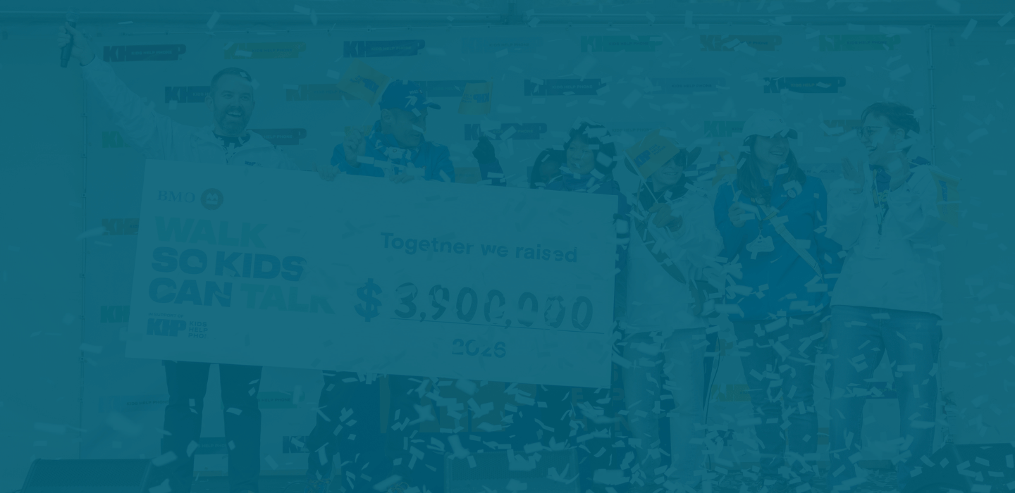A group of people stand on a stage at BMO Walk so Kids Can Talk, holding a large cheque that reads “Together we raised $3,900,000,” while confetti falls around them. 